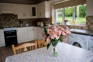 a kitchen with a table with a vase of flowers on it at Cairn view in Mountfield