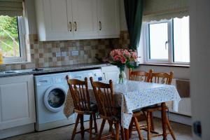 a kitchen with a table with chairs and a washing machine at Cairn view in Mountfield