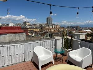 a balcony with white chairs and a view of a city at Tiny Nest Over Naples, Private Panoramic Terrace in Naples