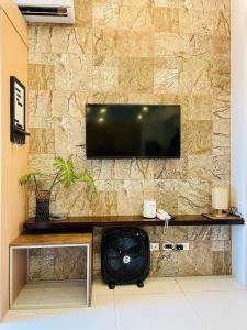 a room with a television on a stone wall at The Wind Escape Netflix-Ready Staycation for 4 in Tagaytay