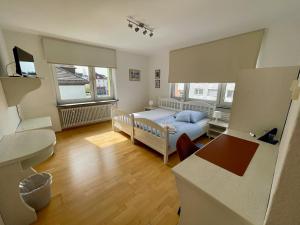 a bedroom with a bed and a desk and two windows at Gästehaus Wilhelma in Gießen