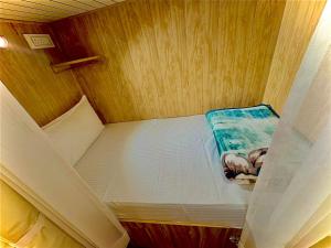 a small bed in a small room with wooden walls at Cannaught Stays in New Delhi +4 photos