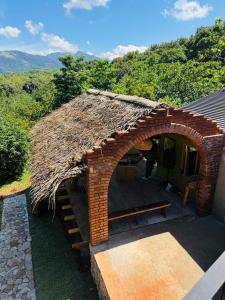 a small brick building with a thatched roof at Heaven's Acres Lodge - Private one Bedroom Cabana in Matale