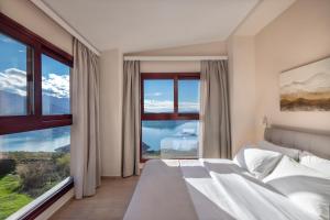 a bedroom with a large bed and large windows at Lake Kremasta Hotel in Neokhórion