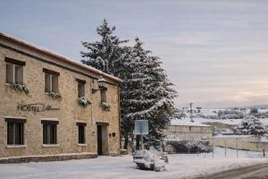 a building in the snow next to a tree at HOSTEL Villanueva in Villanueva de Alcorón