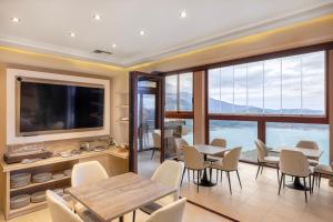 a dining room with tables and chairs and a flat screen tv at Lake Kremasta Hotel in Neokhórion