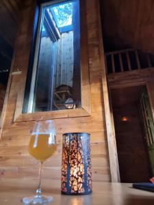 a glass of wine sitting on a table with a window at Gluba Treetop Cabins Elgposten in Harkmark
