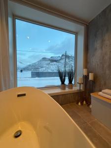 a bath tub in a bathroom with a large window at The View XL in Senja