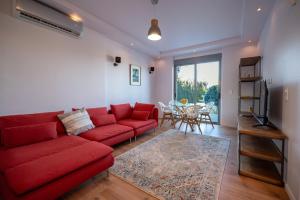 a living room with a red couch and a table at Villa Tata - Private Pool, Garden & Mountain View near the Sea in Metókhi