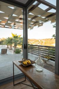 a table with a bowl of fruit and a glass vase at Villa Tata - Private Pool, Garden & Mountain View near the Sea in Metókhi