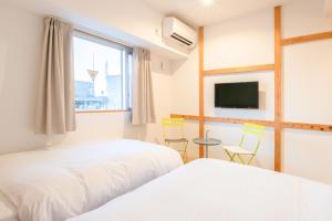 two beds in a room with a window and a tv at Smile Hotel Miyakojima in Miyako-jima