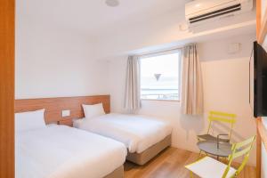 a hotel room with two beds and a window at Smile Hotel Miyakojima in Miyako-jima