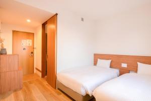 a bedroom with two beds and a cabinet at Smile Hotel Miyakojima in Miyako-jima