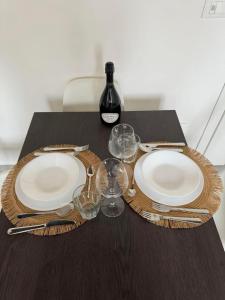 a table with two plates and a bottle of wine at Frida Apartment in Chioggia