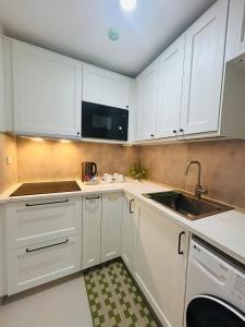 a white kitchen with white cabinets and a sink at Unit 509 - One Pontefino Tower in Batangas City