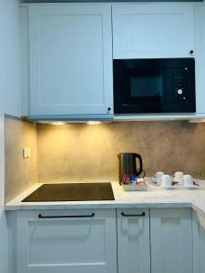 a kitchen with white cabinets and a black microwave at Unit 509 - One Pontefino Tower in Batangas City +3 photos