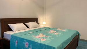 a bed with a blue blanket with flowers on it at Breezy Resort in Arugam Bay +25 photos