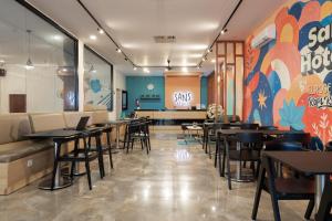 a restaurant with tables and chairs and a colorful wall at Sans Hotel Elrose Place in Samarinda