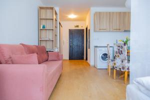 a living room with a pink couch and a kitchen at Студио 8 Уютна Почивка in Hisarya