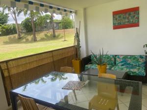 a dining room with a glass table and a couch at Location vacances Fun sous les gommiers in Sainte-Luce