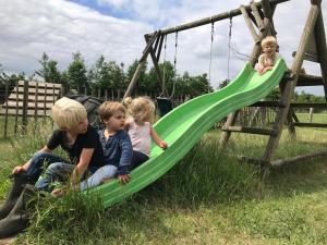 three children playing on a swing set at Landhoeve in Oosterwolde