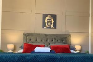 a bedroom with a bed with red pillows and a statue at Springfield Apartment - Train to Glasgow or Edinburgh - Private Parking & Wifi in Airdrie