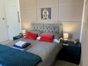 a bedroom with a large bed with red pillows at Springfield Apartment - Train to Glasgow or Edinburgh - Private Parking & Wifi in Airdrie