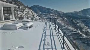 a building with snow on the ground next to a mountain at The Terraces by 12th Avenue in Murree