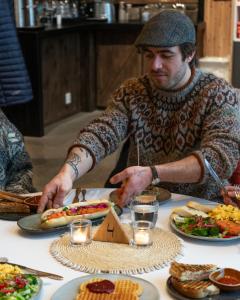 a man sitting at a table with plates of food at Lofoten Beach Camp in Ramberg +27 photos