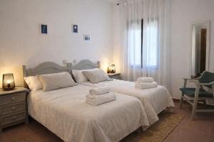 a white bedroom with two beds with towels on them at HOSTEL Villanueva in Villanueva de Alcorón