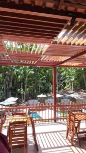 a wooden deck with tables and chairs and a pool at Eco Hotel Mãe De Sagui in Castanhal