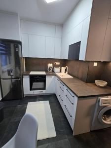 a kitchen with white cabinets and a sink and a dishwasher at Ákos Apartman in Székesfehérvár