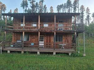 a wooden house with a deck in a field at Beaver Creek Guest Ranch in Blue