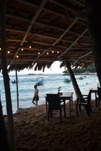 a person walking on a beach with a table and chairs at Check Point in Unawatuna