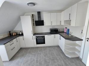 a white kitchen with white cabinets and a sink at Torwirt Apartments in Herrieden