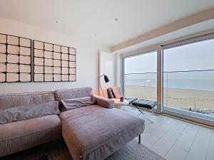 ein Wohnzimmer mit Sofa und Blick auf den Strand in der Unterkunft Rubensplein 7p, 4 adults & 3 kids - free parking in Knokke-Heist