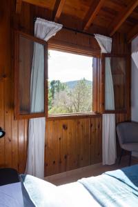a bedroom with a large window in a wooden wall at Casa de Madera I - Naturaleza y Experiencias in Bicorp