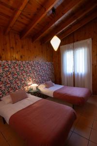 two beds in a room with wooden walls at Casa de Madera I - Naturaleza y Experiencias in Bicorp