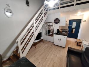 a white staircase in a living room with a kitchen at Studio Duplex in Balaruc-les-Bains