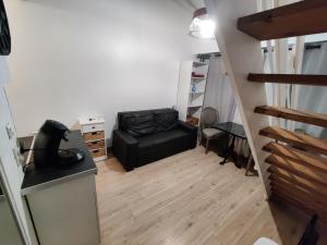 a living room with a black leather chair and stairs at Studio Duplex in Balaruc-les-Bains +2 photos