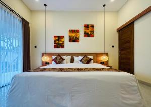 a bedroom with a large white bed with two lamps at Golden Villa Lovina in Lovina +26 photos