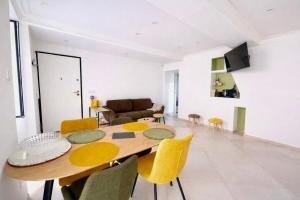 a dining room with a wooden table and yellow chairs at Appartement T3 Place du Marché in Bastia