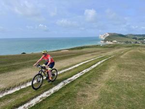 a man riding a bike on a dirt road near the ocean at The Sandown - Seafront, Sandown, Isle of Wight - CAR FERRY TICKET from 109 Pounds in Sandown