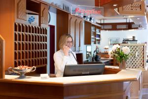 a woman sitting at a counter talking on a cell phone at Hotel Montana Lauenau in Lauenau