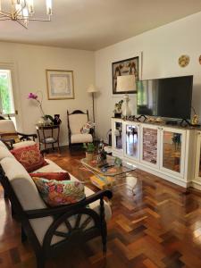 a living room with a couch and a flat screen tv at Pousada Casa Thede in São Salvador