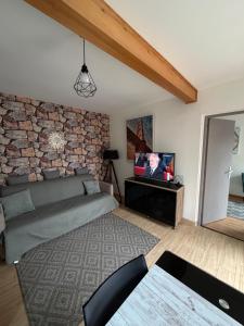 a living room with a bed and a stone wall at Studio indépendant Lisieux in Lisieux