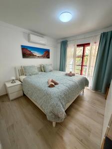 a bedroom with a large bed with blue curtains at Cozy Garden by the Beach in Playa del Cura +30 photos
