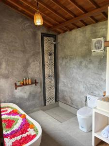 a bathroom with a bath tub and a toilet at Wana Ayu Jelijih Villas by Dhananjaya Hospitality in Tampaksiring