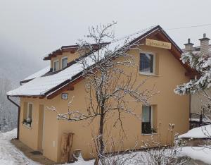 a yellow house with snow on the roof at Ubytovanie Málika in Čierny Blh