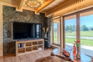 a living room with a tv and a stone wall at Domki Góralska Przystań in Białka Tatrzańska